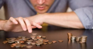 a person hovering their fingers over a pile of coins on a table