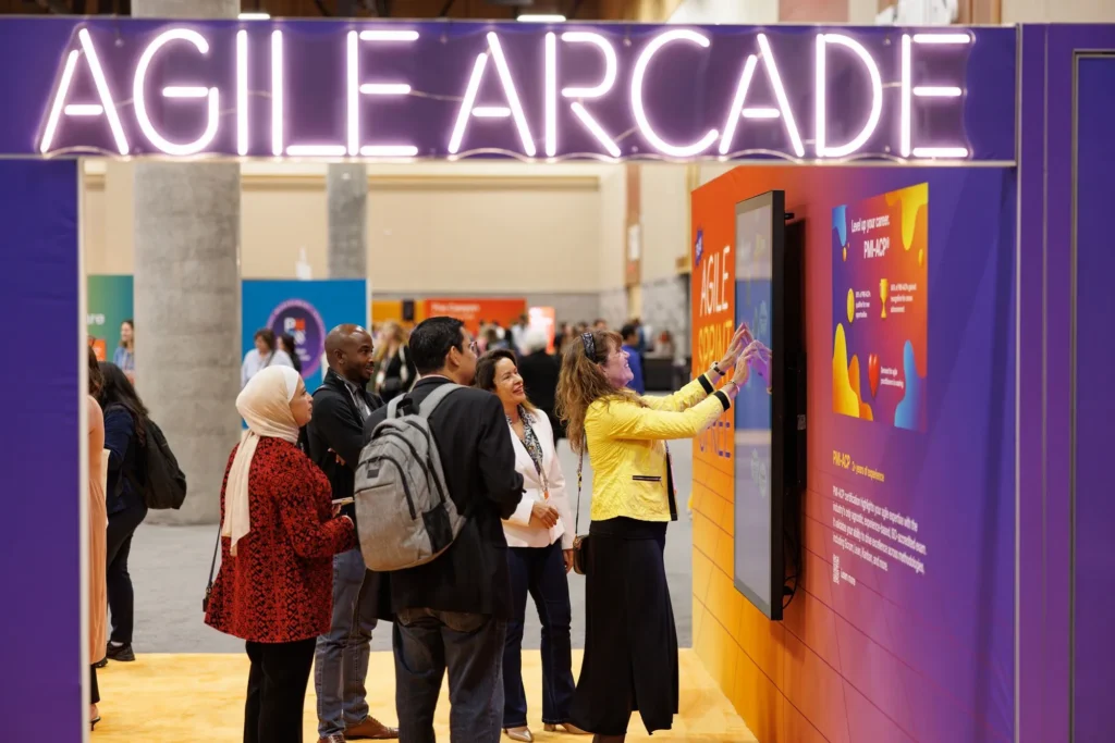 Konferenzteilnehmende nutzen ein Gerät im Agile Arcade-Bereich auf dem PMI Global Summit
